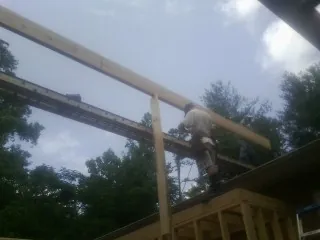Carpenter setting a ridge beam over a new addition frame — Ice Dam Removal by Roofing Brothers in Sweeny