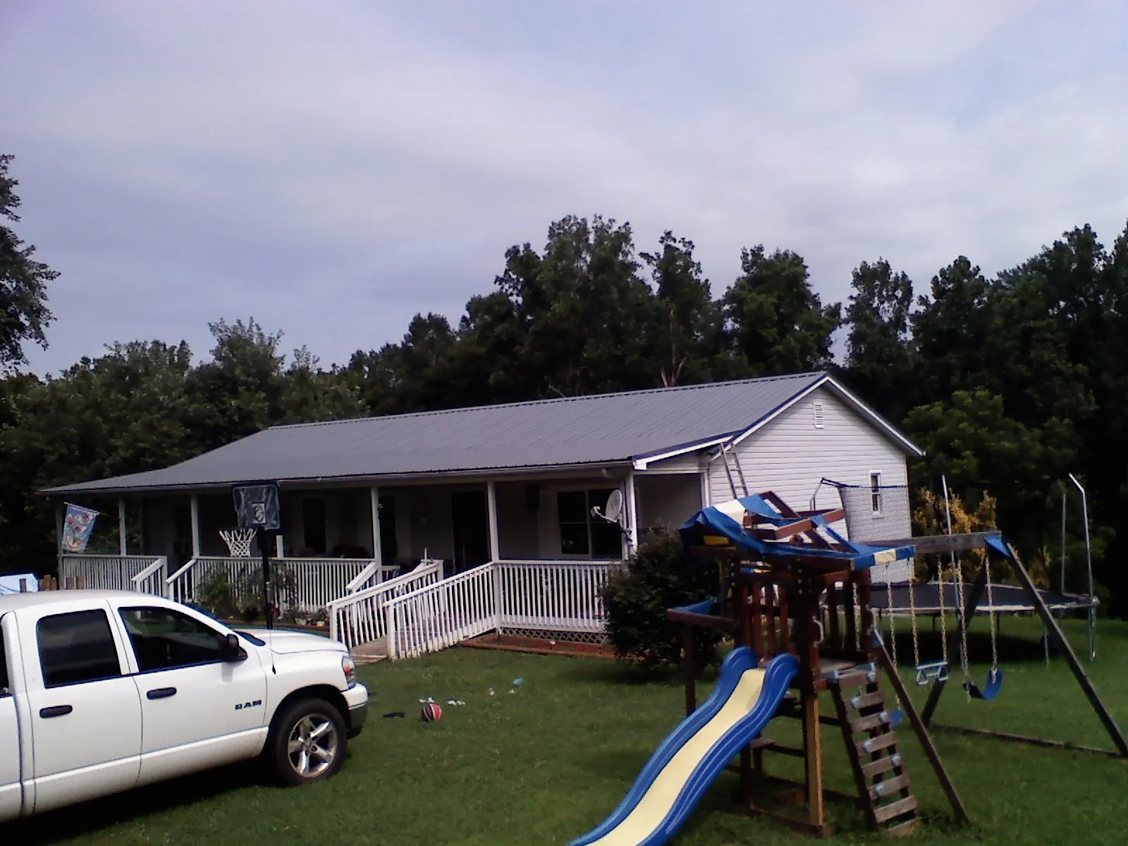 Dark metal roof on a country home with a full length front porch in Sweeny