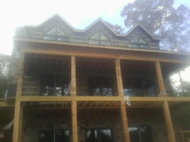 Dormers and porch framing on a large log home under construction — Roof Coating work by our crew in Sweeny