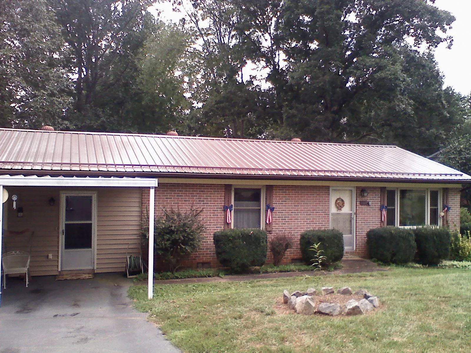 Bronze metal roof and carport on a brick ranch home — Roof Repair work by our crew in Sweeny